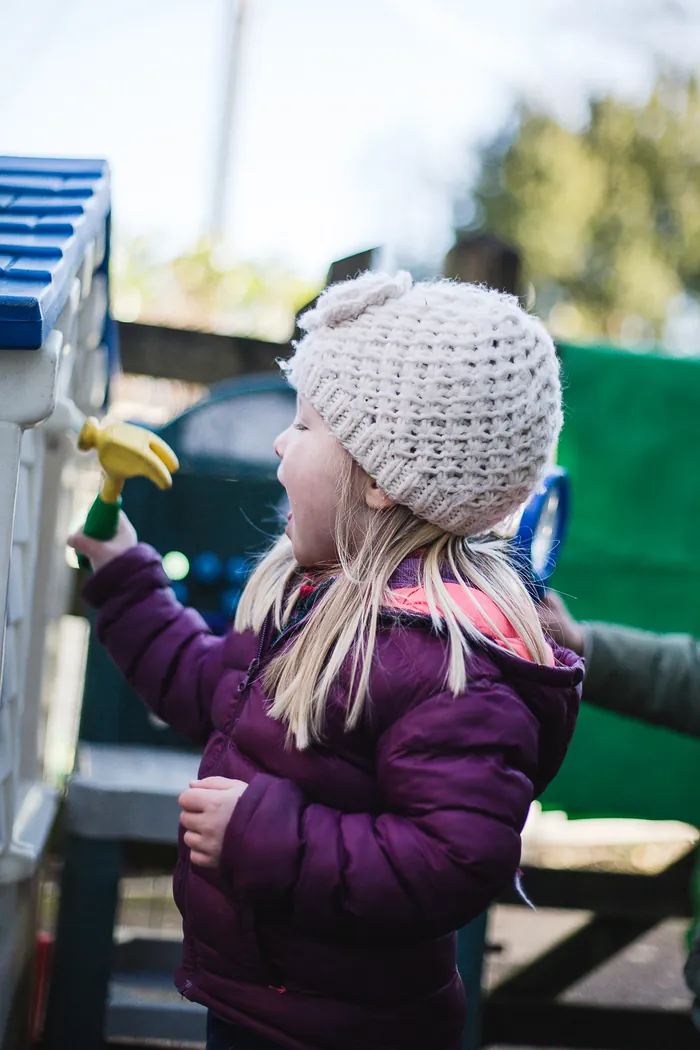 A girl in a woolly hat playing outside
