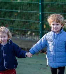 Two children holding hands outside