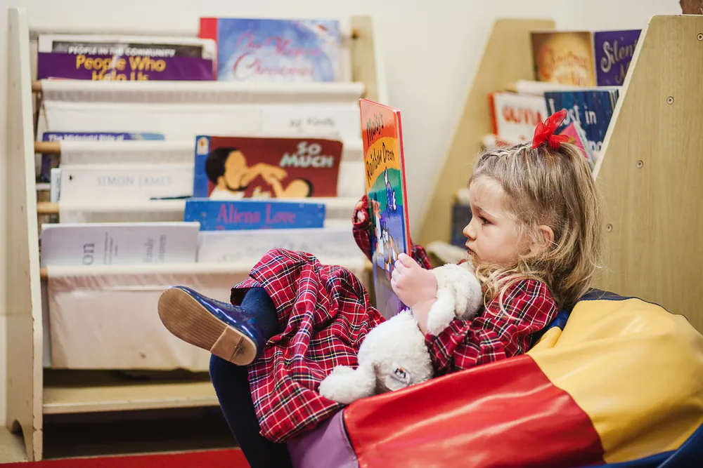 A girl sitting in the book corner, reading