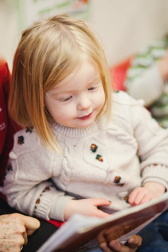 A girl looking at a picture book with an adult