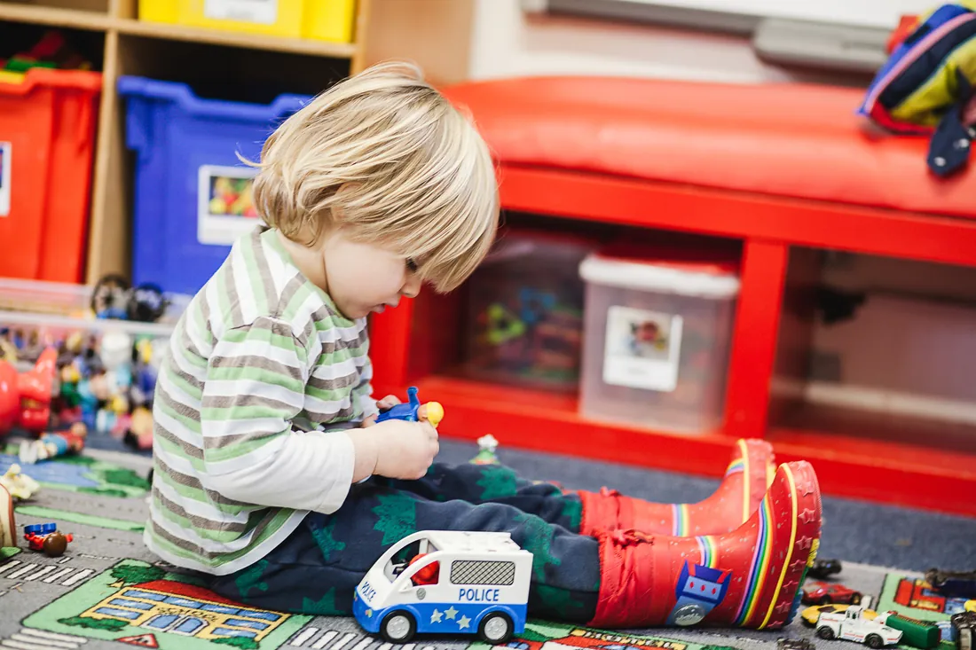 A boy playing with toy cars on the play mat