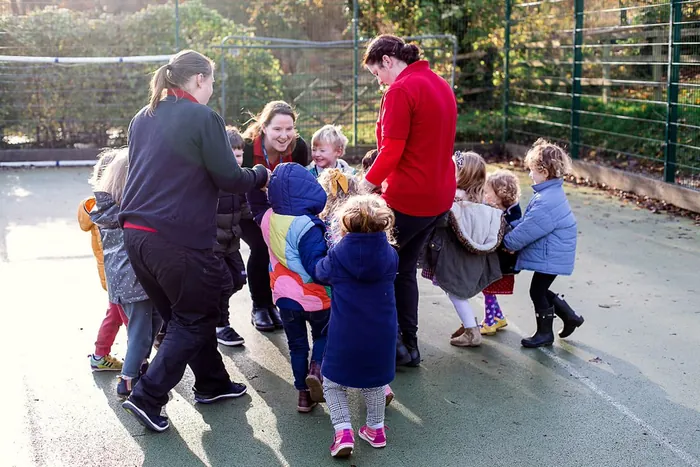 Children and staff playing a circle game in the playground