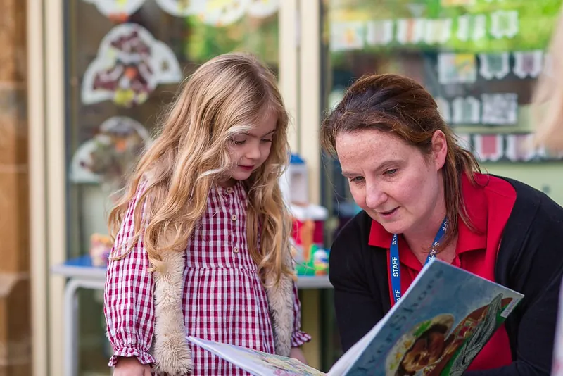 A girl sharing a book with a member of staff
